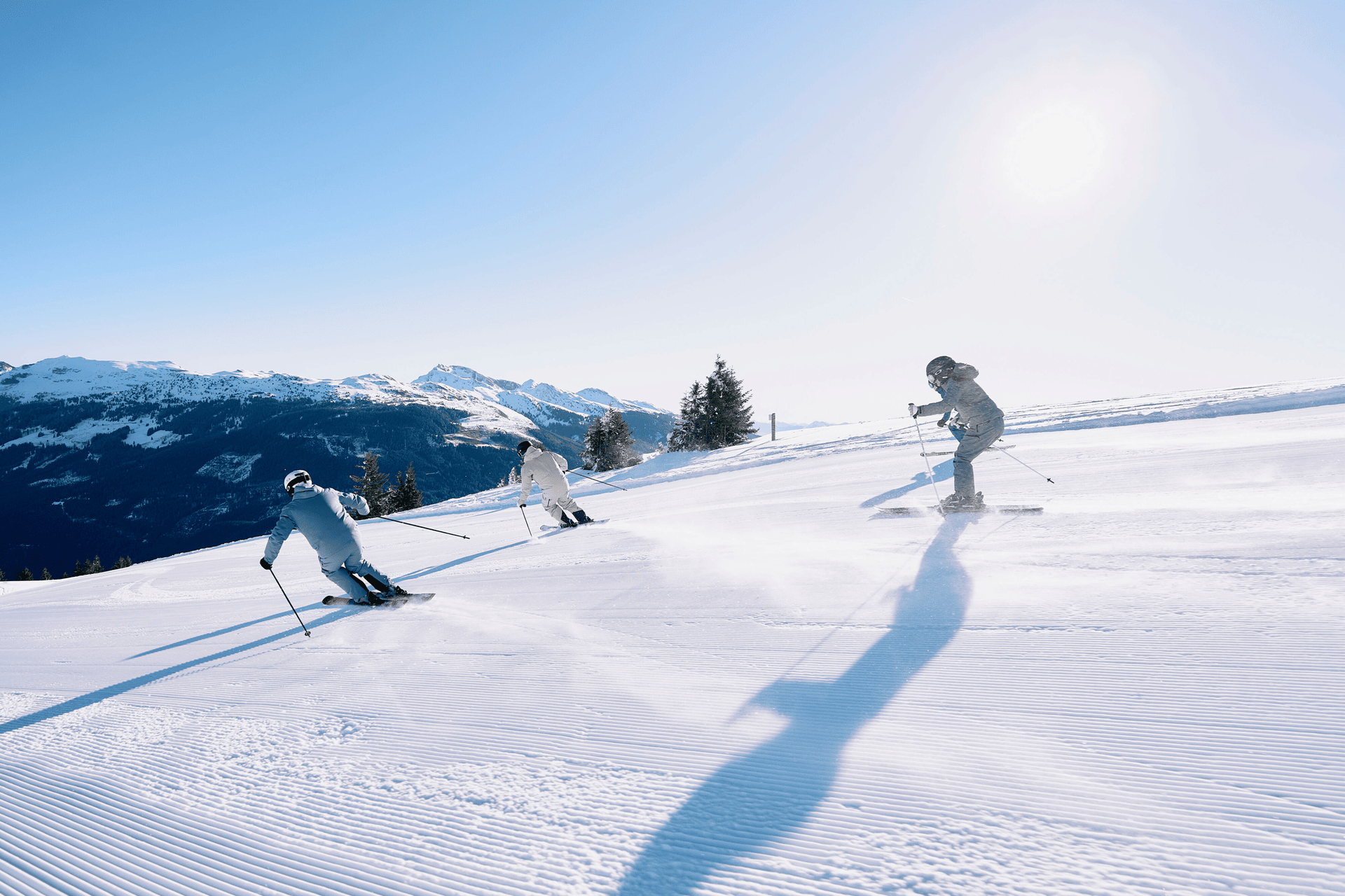 3 Skifahrer fahren die Piste hinunter