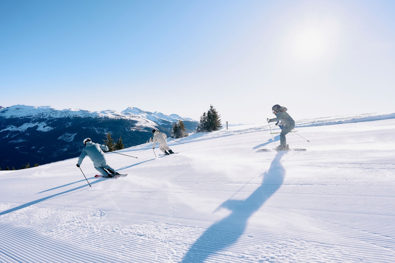 3 Skifahrer fahren die Piste hinunter