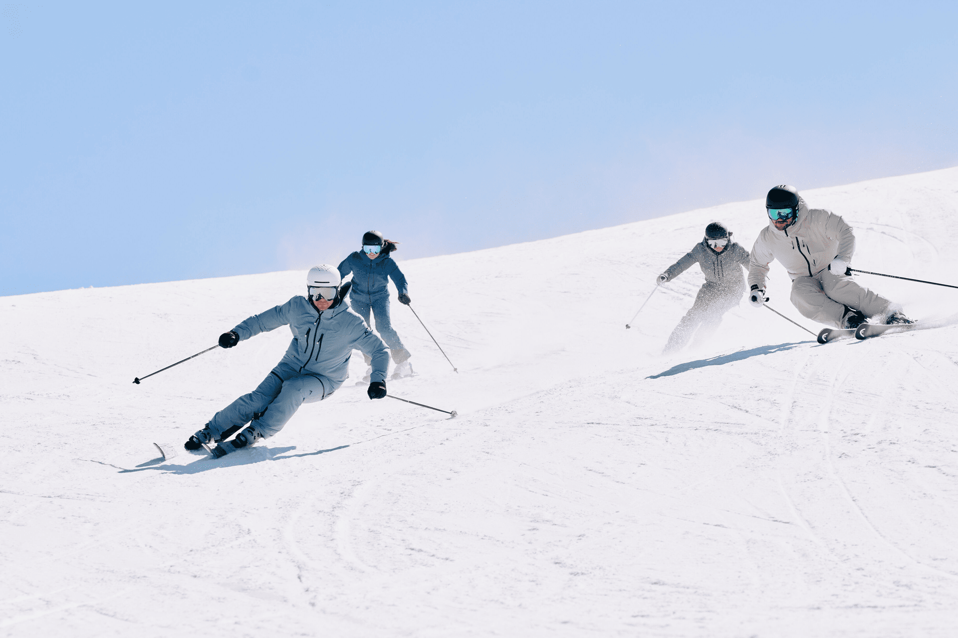 4 Skifahrer fahren die Piste hinunter