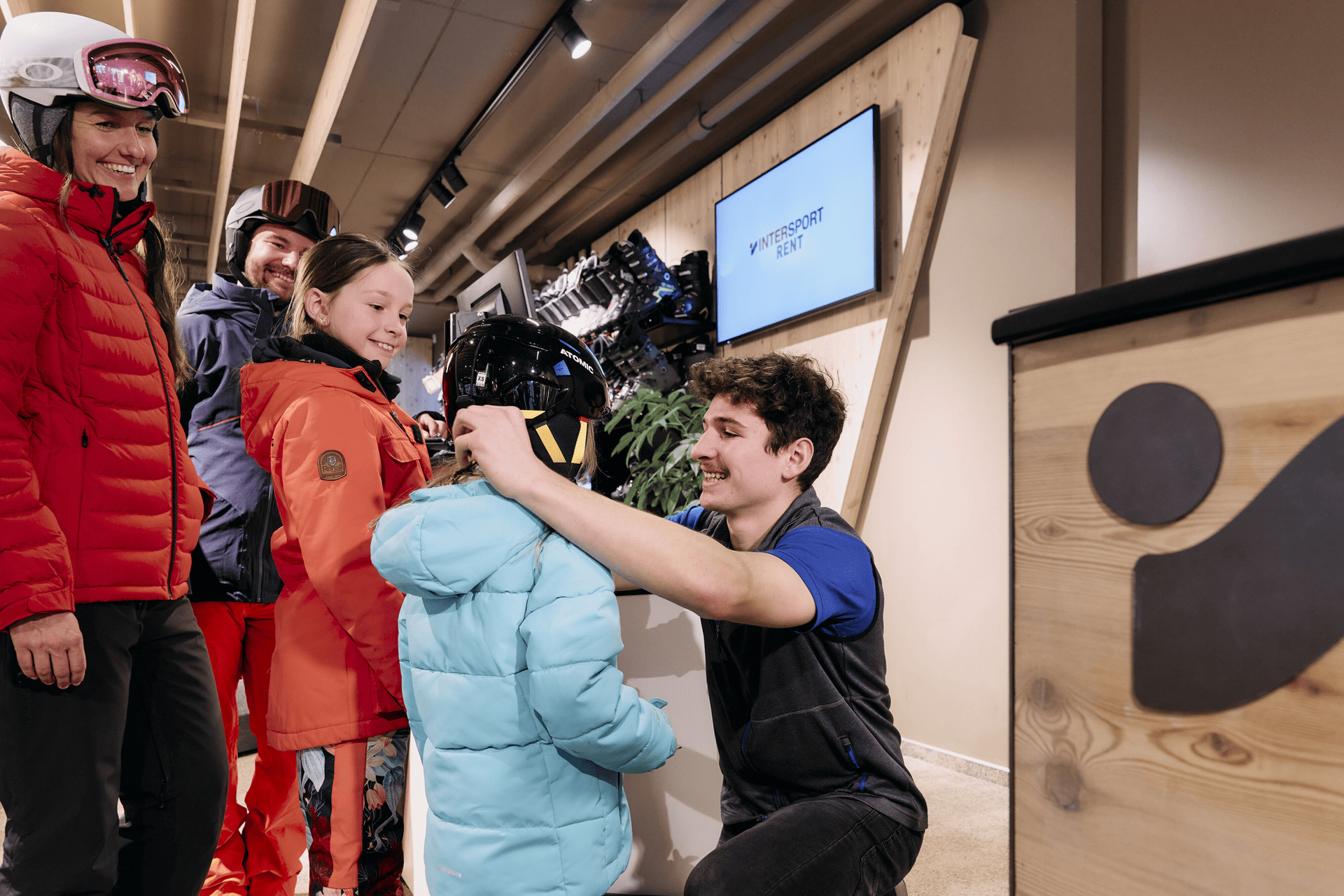 Inersport-Mitarbeiter trägt Skihelm für Kind
