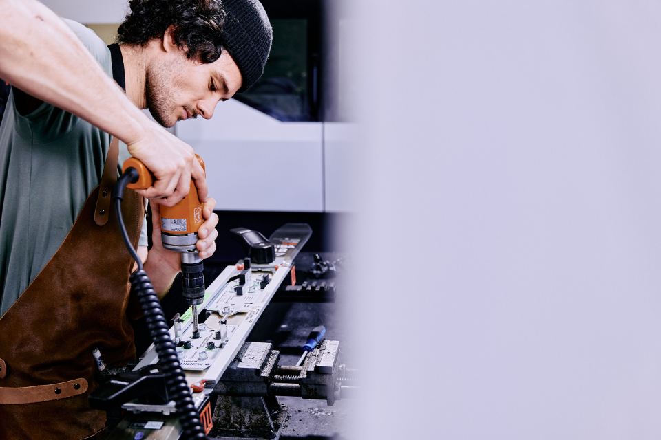 Mitarbeiter schraubt auf einem Ski